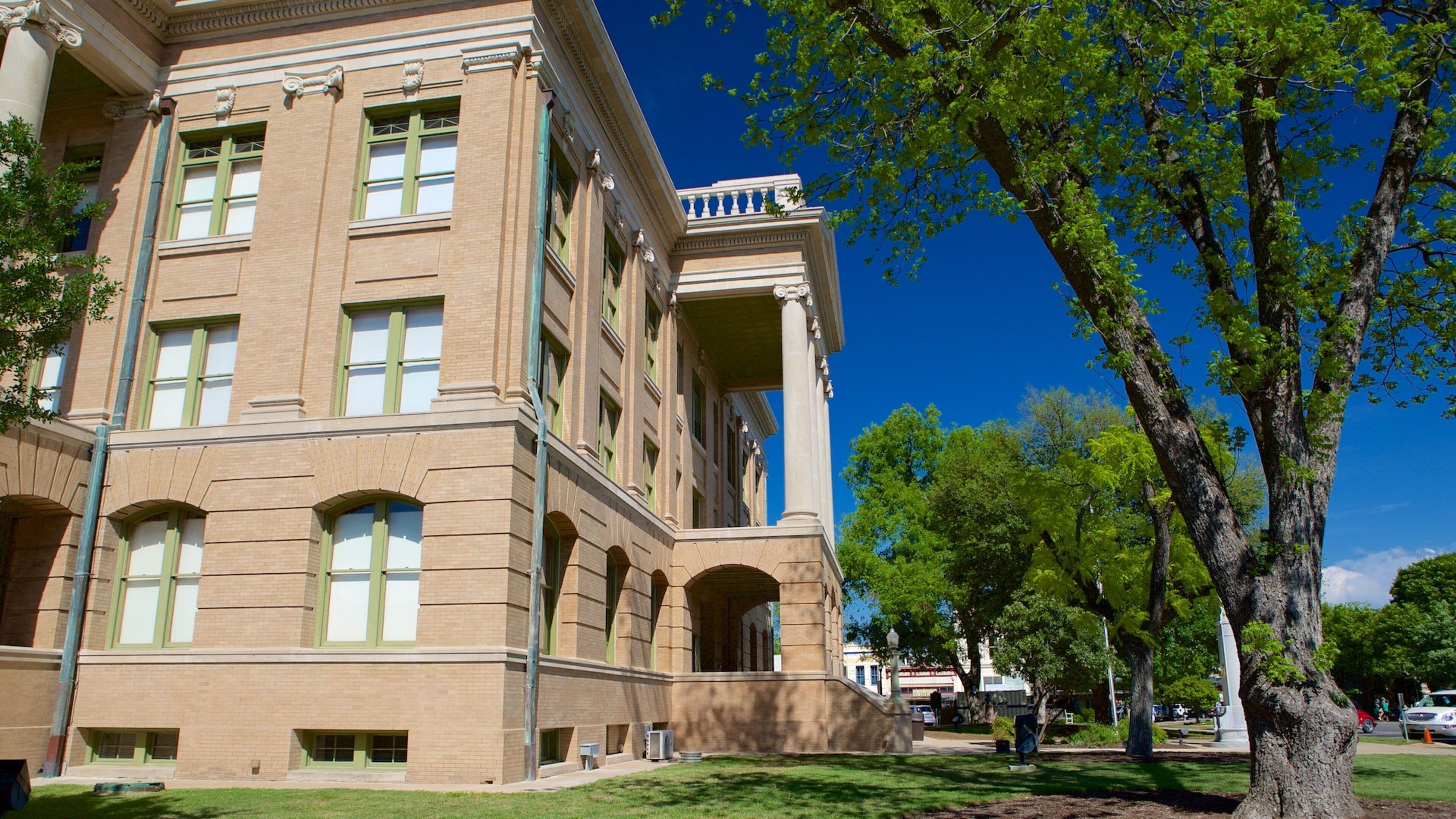 A large brick building with green-framed windows and a balcony.