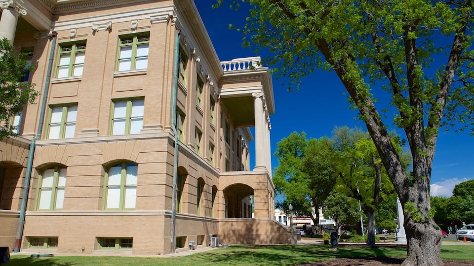 A large brick building with green-framed windows and a balcony.