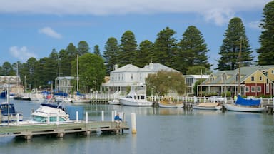A marina with various boats docked, surrounded by residential buildings and tall trees.