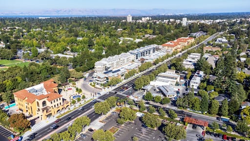Aerial view of commercial and residential areas of Menlo Park, California toward Palo Alto along El Camino Real Road near Middle Avenue. Backdrop distant San Francisco Bay and mountains