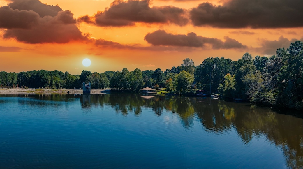 a stunning aerial panoramic shot of the blue waters of Lake Peachtree with vast miles of lush green trees and boats docked along the lake with powerful clouds at sunset in Peachtree City Georgia USA