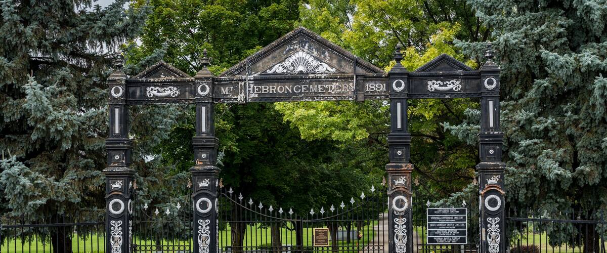 A historic gate with intricate designs and the inscription "Mt. Hebron Cemetery 1891".