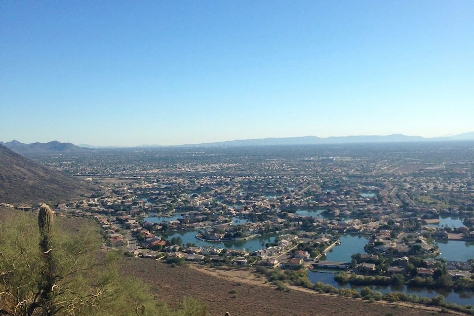 A mountainous landscape with a town below, featuring a large body of water and sparse vegetation.