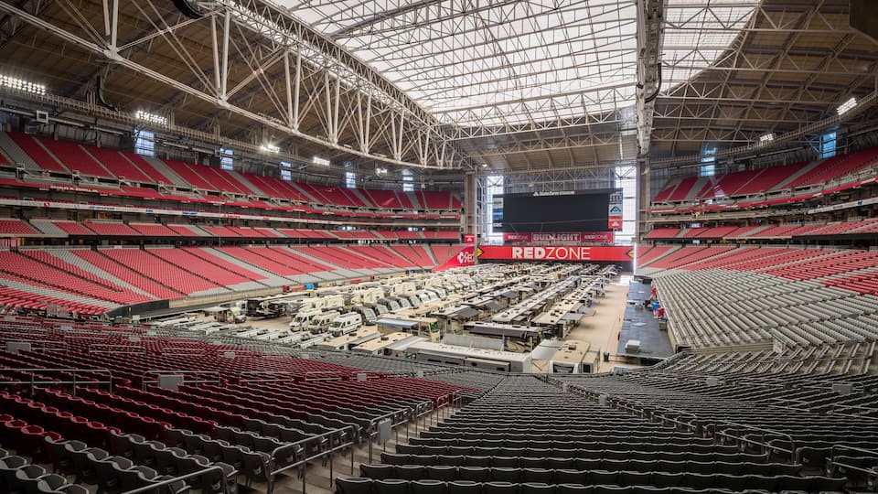 An empty stadium with red seats and a large screen displaying "REDZONE".