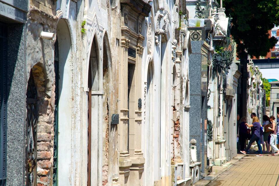 A row of ornate, historic buildings with intricate carvings and a paved walkway.
