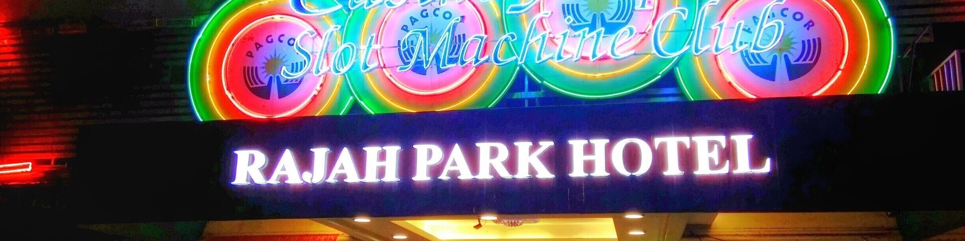 Hotel Rajah Park, com um letreiro de neon anunciando o Casino Slot Machine Club.