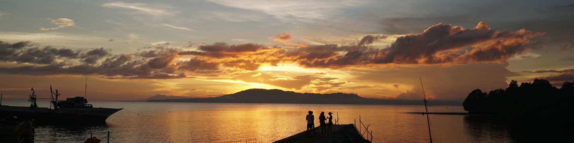 Um pôr do sol sobre um lago calmo, com barcos e um cais.