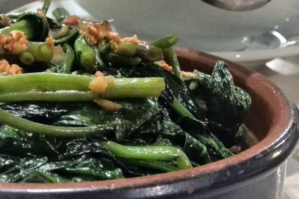 Un tazón de vegetales cocidos con trozos crujientes por encima.