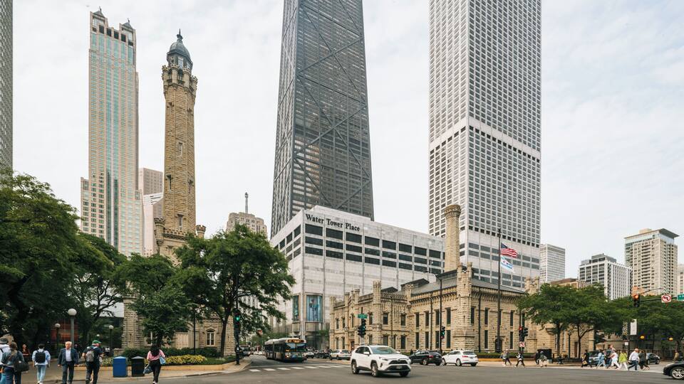 A cityscape with tall buildings, including a historic tower and modern skyscrapers.