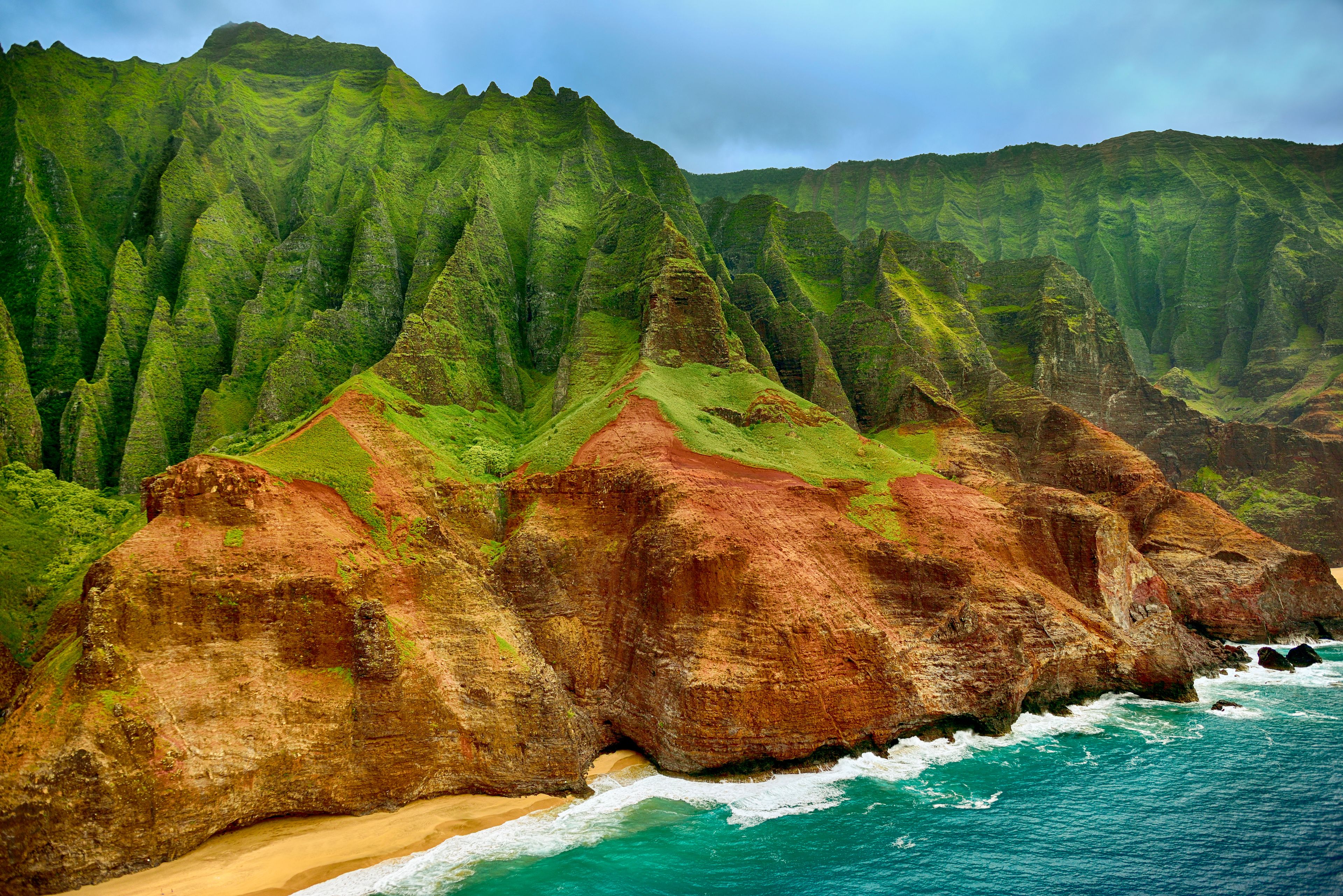 A coastal landscape with green hills and a sandy beach.