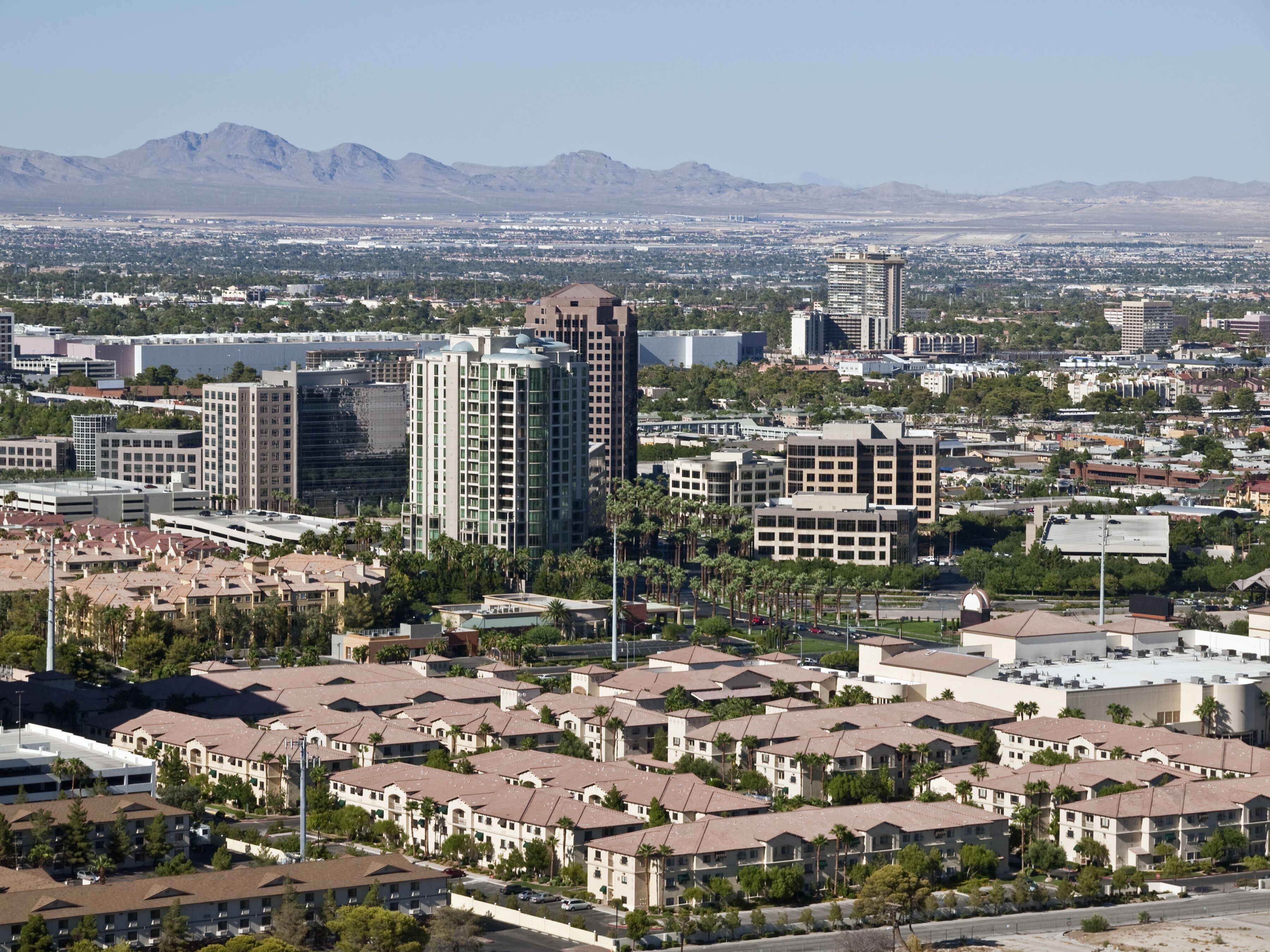 A cityscape with residential buildings, a large hotel, and mountains in the background.