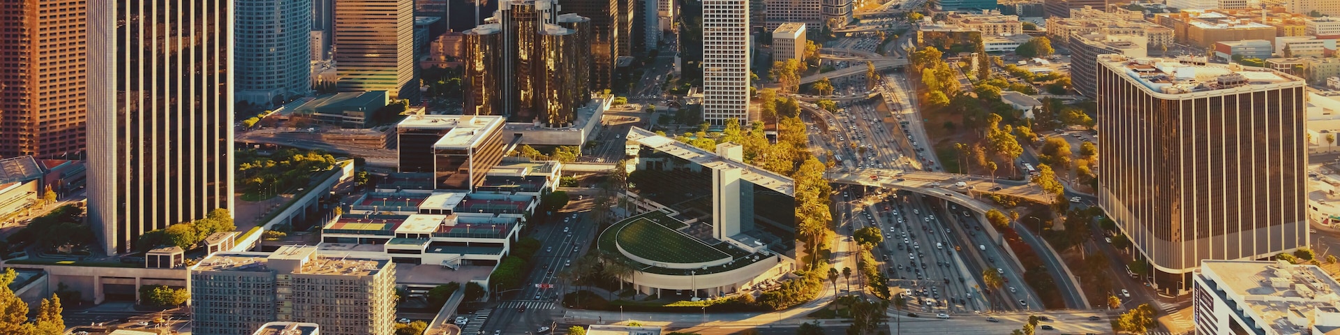 Paisagem urbana com arranha-céus, uma autoestrada e um cruzamento circular.