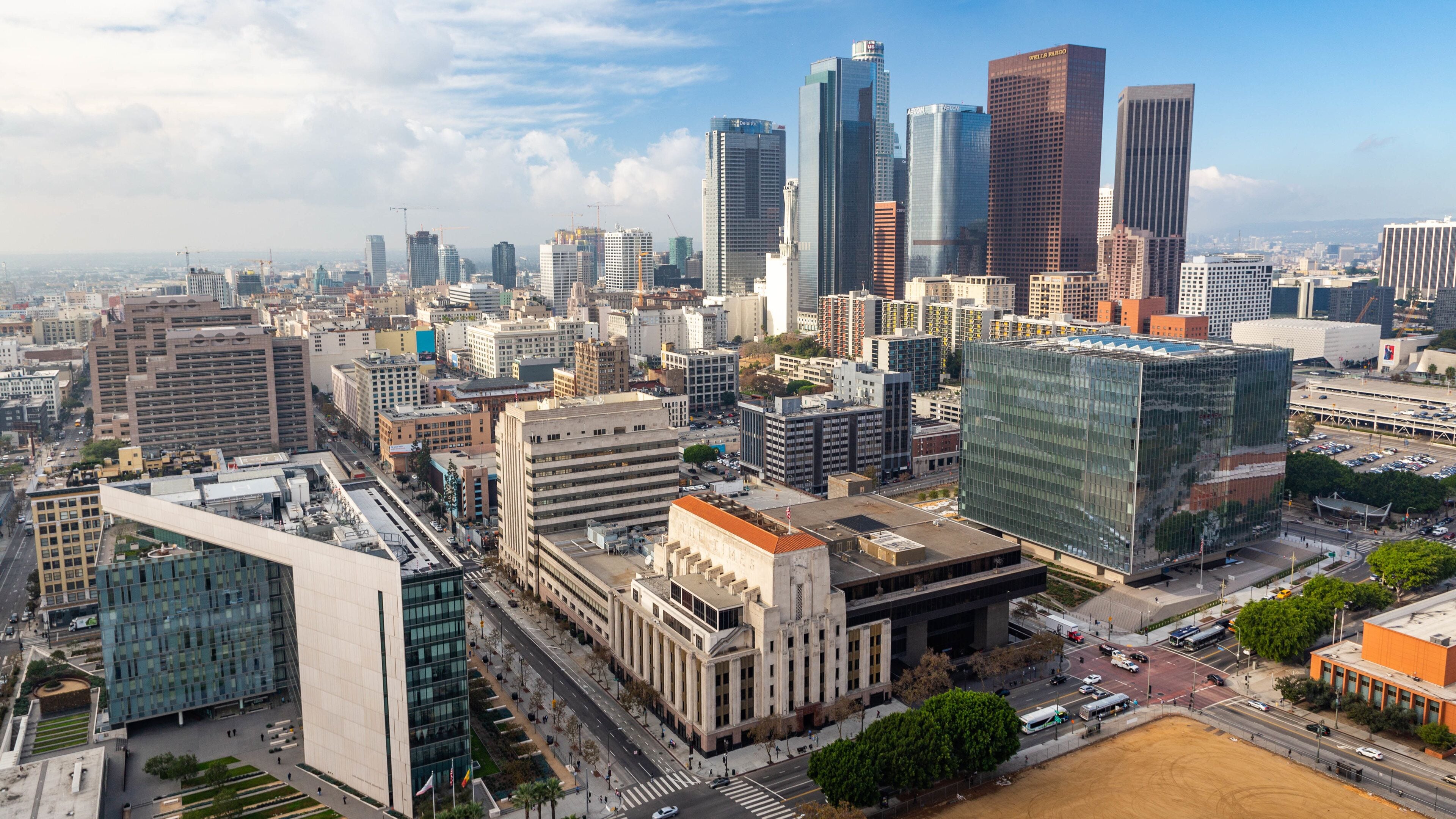 A cityscape with modern skyscrapers, a historic building with 'The Times' logo, and a mix of commercial and residential buildings.