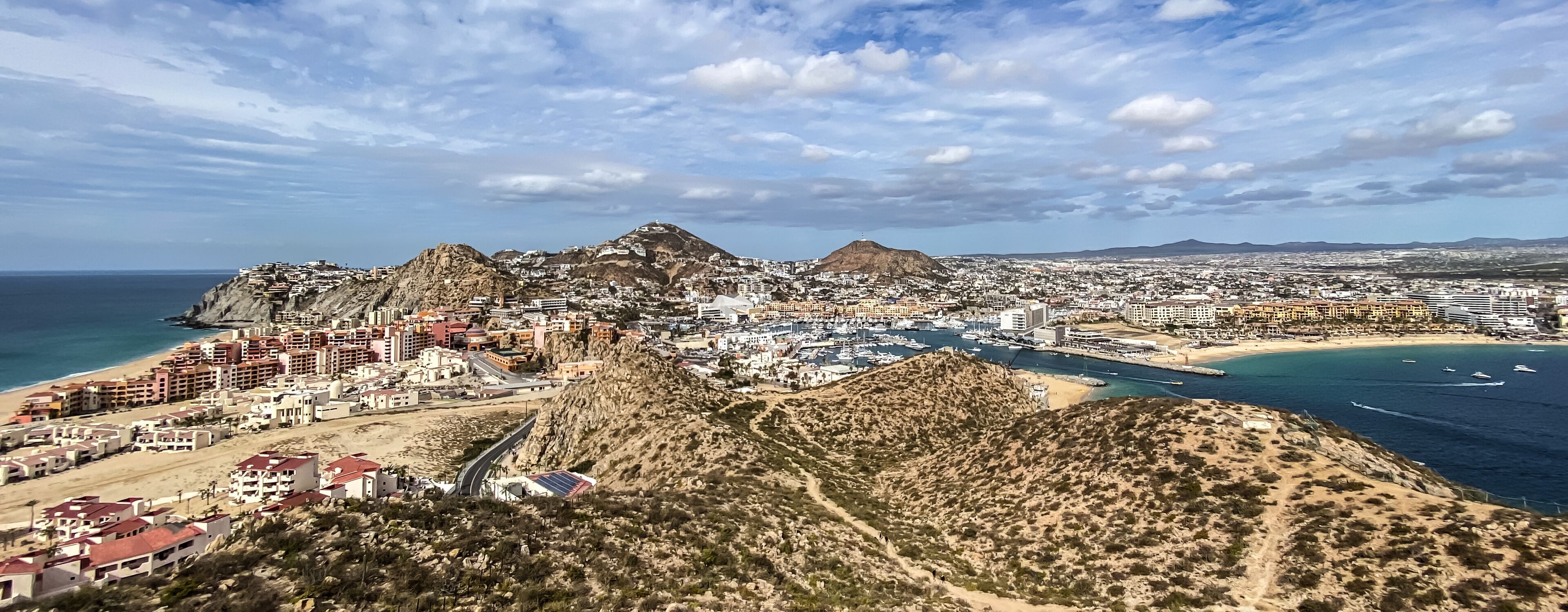 A coastal city with a prominent mountain, a marina, and a beach.