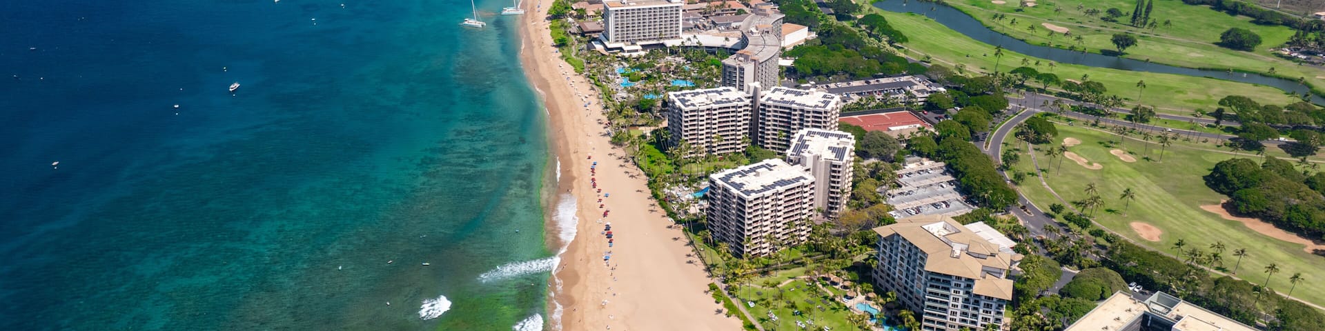 A coastal resort area with a beach, ocean, and golf course.