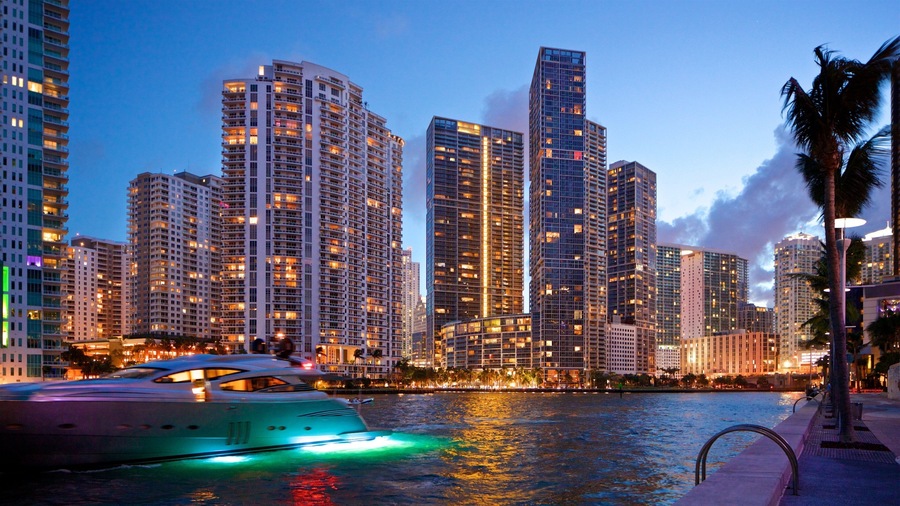 A city skyline with high-rise buildings and a yacht on the water.