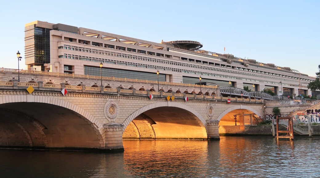 A bridge with arches over a river, a modern building with multiple floors, and decorative railings.