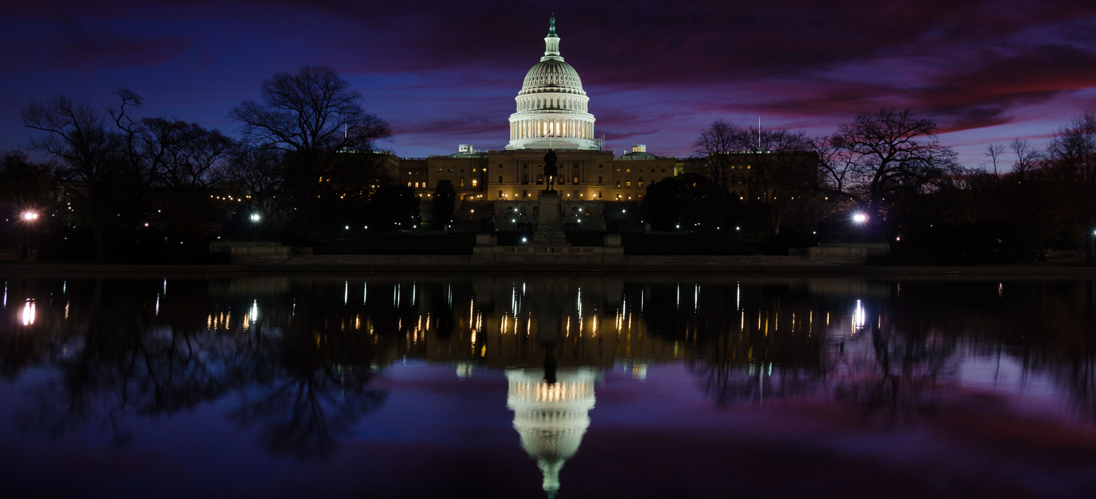 The Capitol building at dusk with its reflection in a body of water.