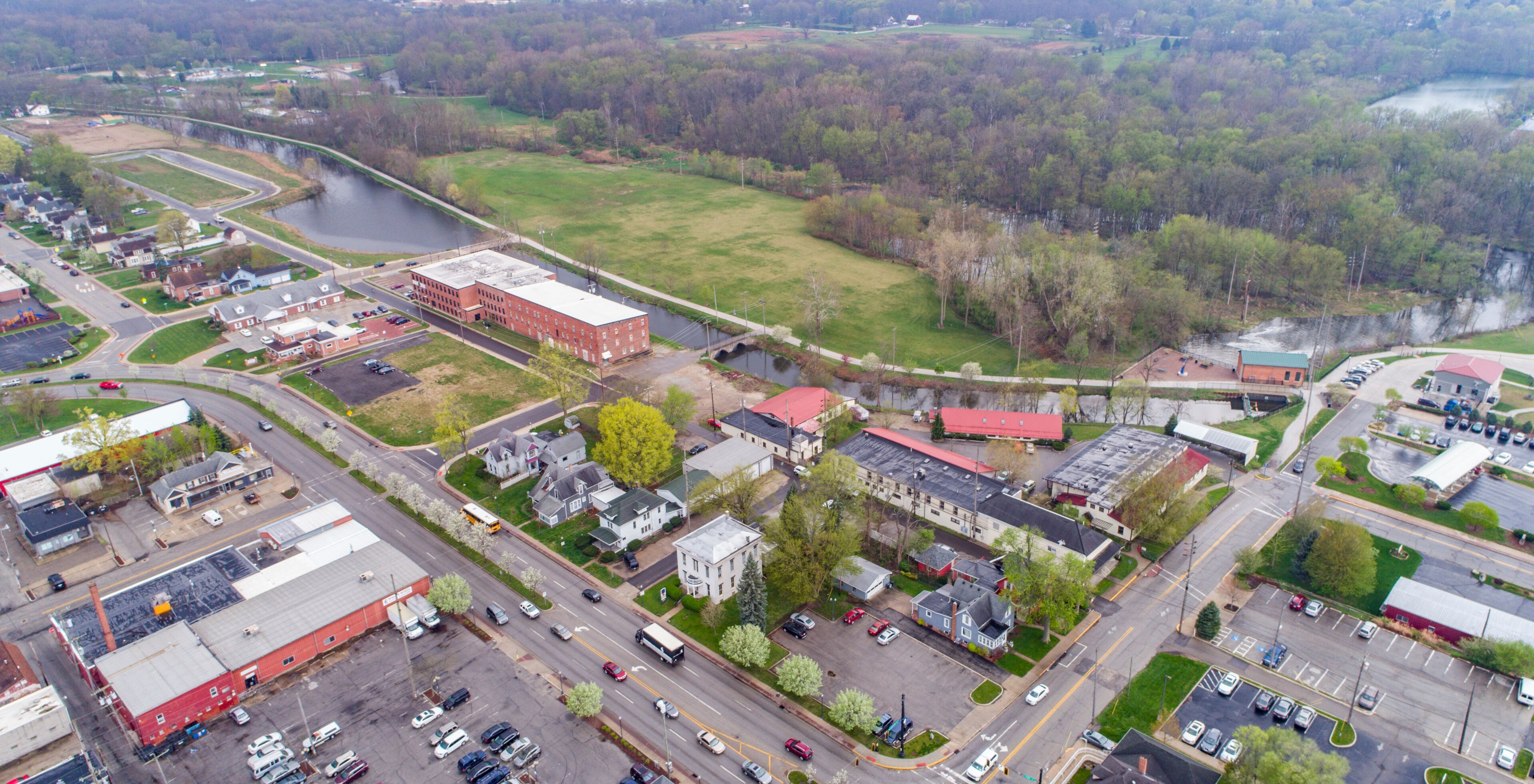 An aerial view of a town with a river, industrial buildings, and a bridge.
