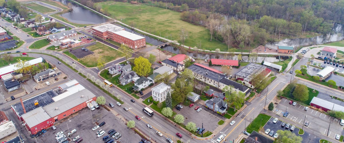 An aerial view of a town with a river, industrial buildings, and a bridge.