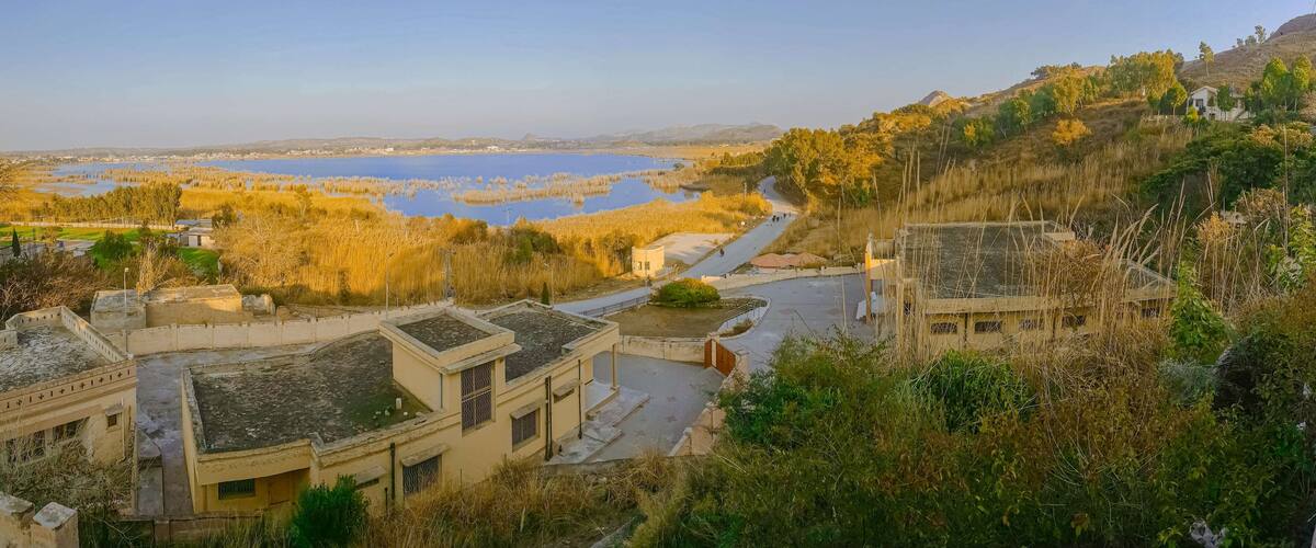 A lakeside village with traditional architecture, a winding road, and surrounding hills.