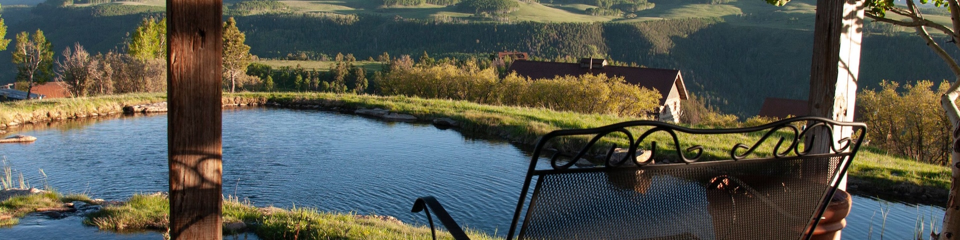 Un banco con vistas a un río y montañas al fondo.