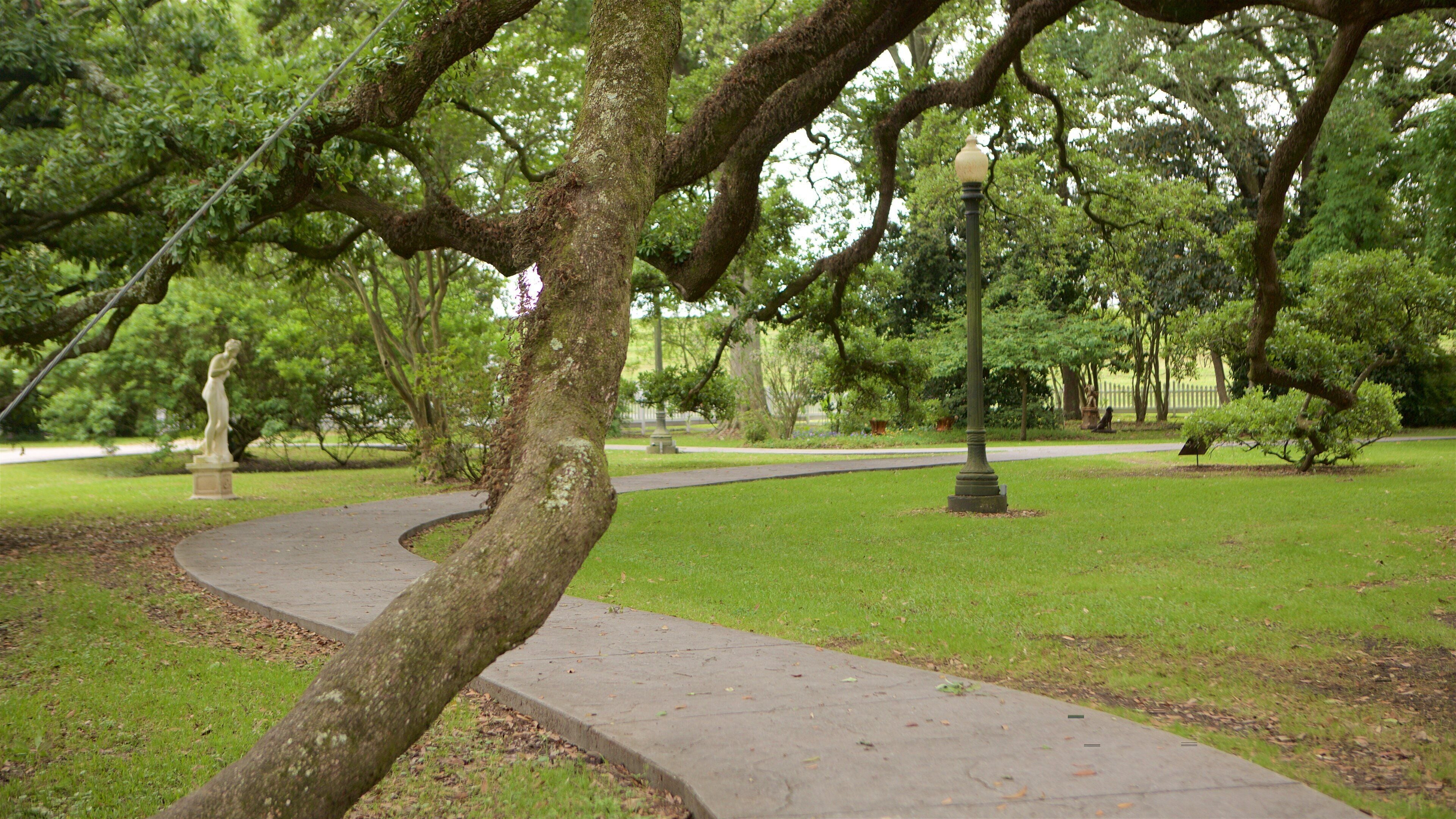 A park with a winding path, a statue, and a lamppost.