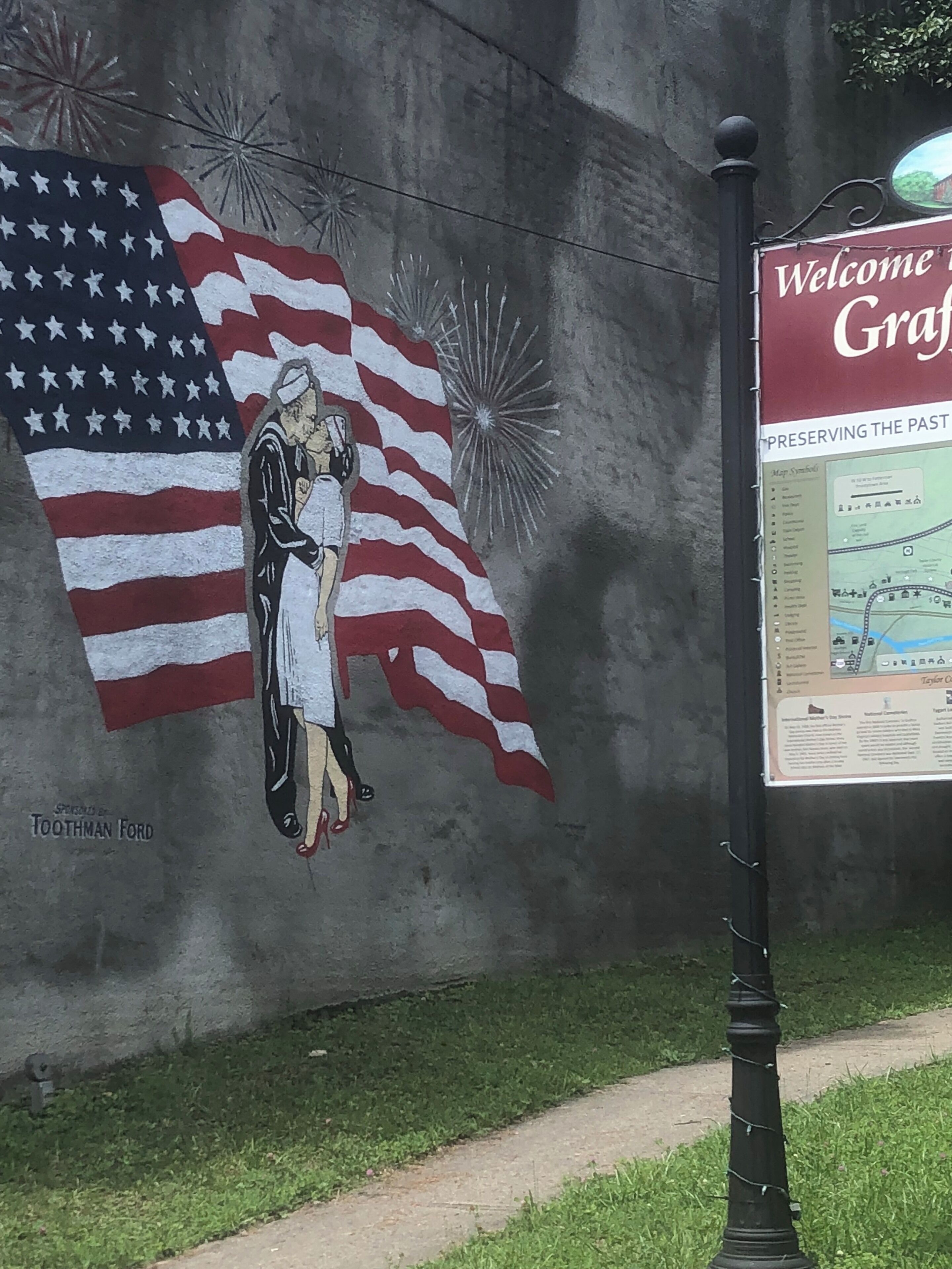 A mural of a woman and an American flag on a wall, with a sign that reads "Welcome to Graff."