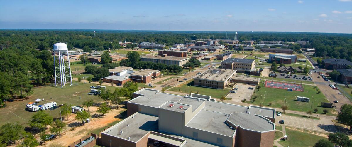 An aerial view of a campus with multiple buildings, parking lots, and a water tower.
