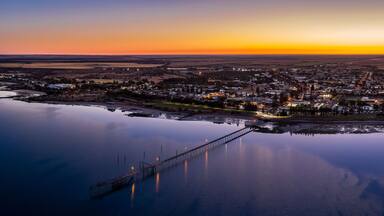 A coastal town at sunset with a bridge extending into the water.