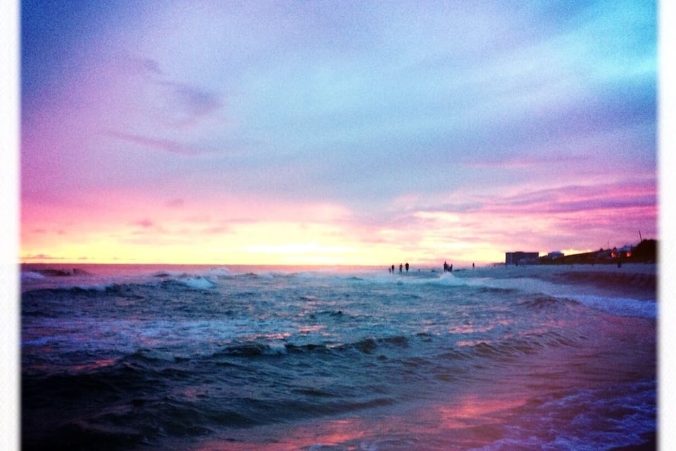 Una playa al atardecer con olas y un cielo colorido.