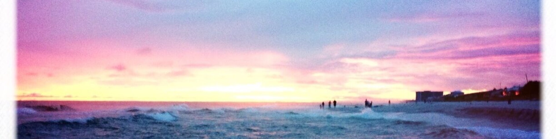 Una playa al atardecer con olas y un cielo colorido.