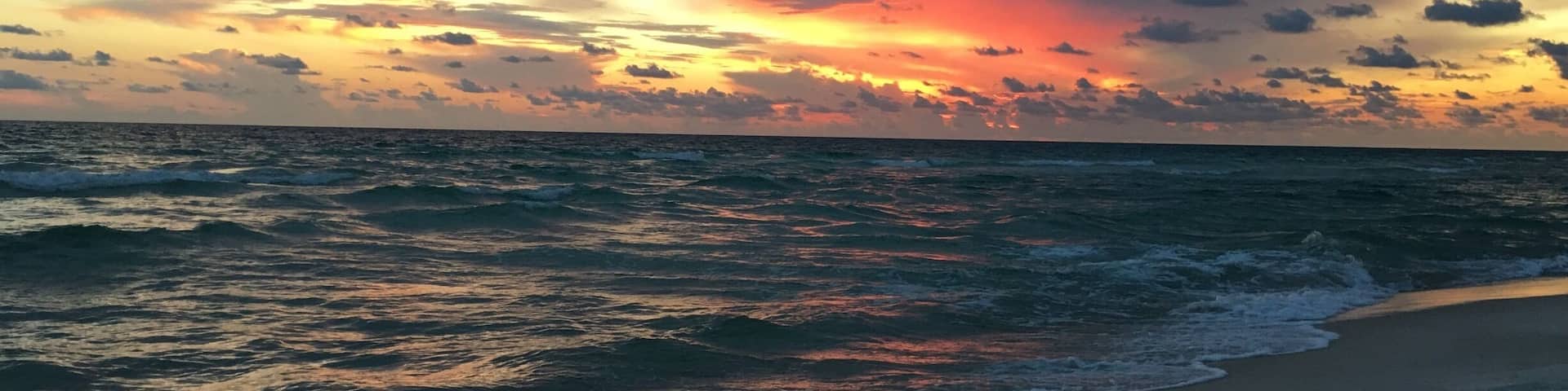 Une plage avec des vagues au coucher du soleil.