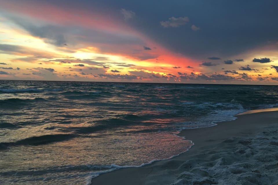 Une plage avec des vagues au coucher du soleil.