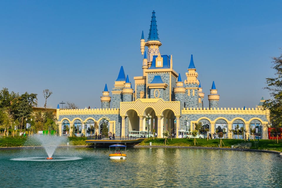 A castle-like building with multiple towers and a fountain in front.