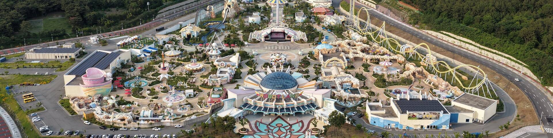 Un parque de atracciones con montañas rusas y una gran estructura con forma de flor en el centro.