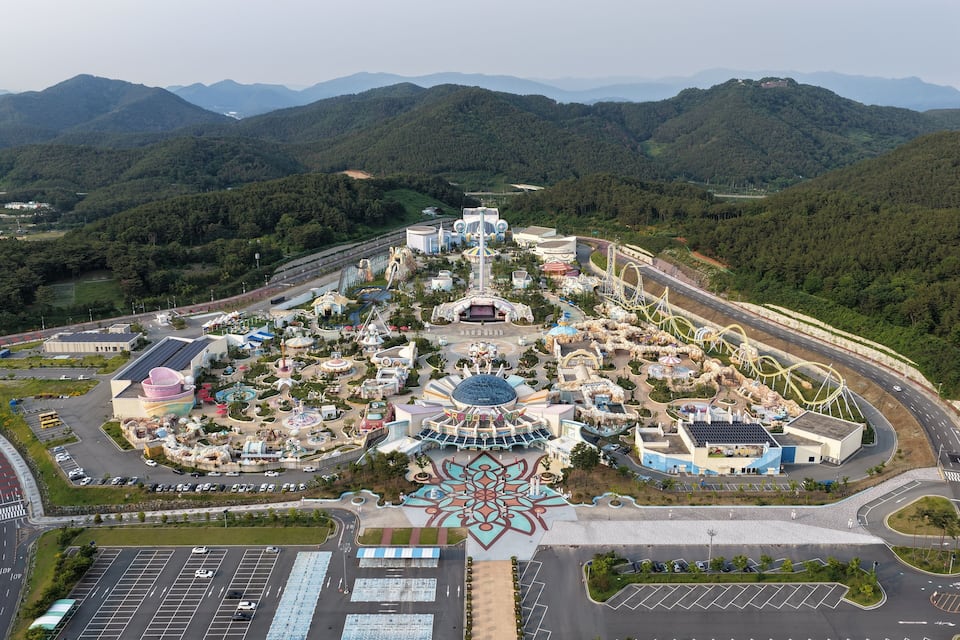 An amusement park with roller coasters and a large flower-like structure in the center.