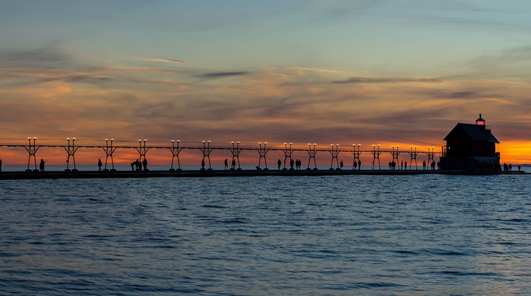 Grand Haven Lighthouse Michigan on Lake Michigan at sunset during the winter with beautiful colors and the structures and people silhouetted. Hot from North Pier.