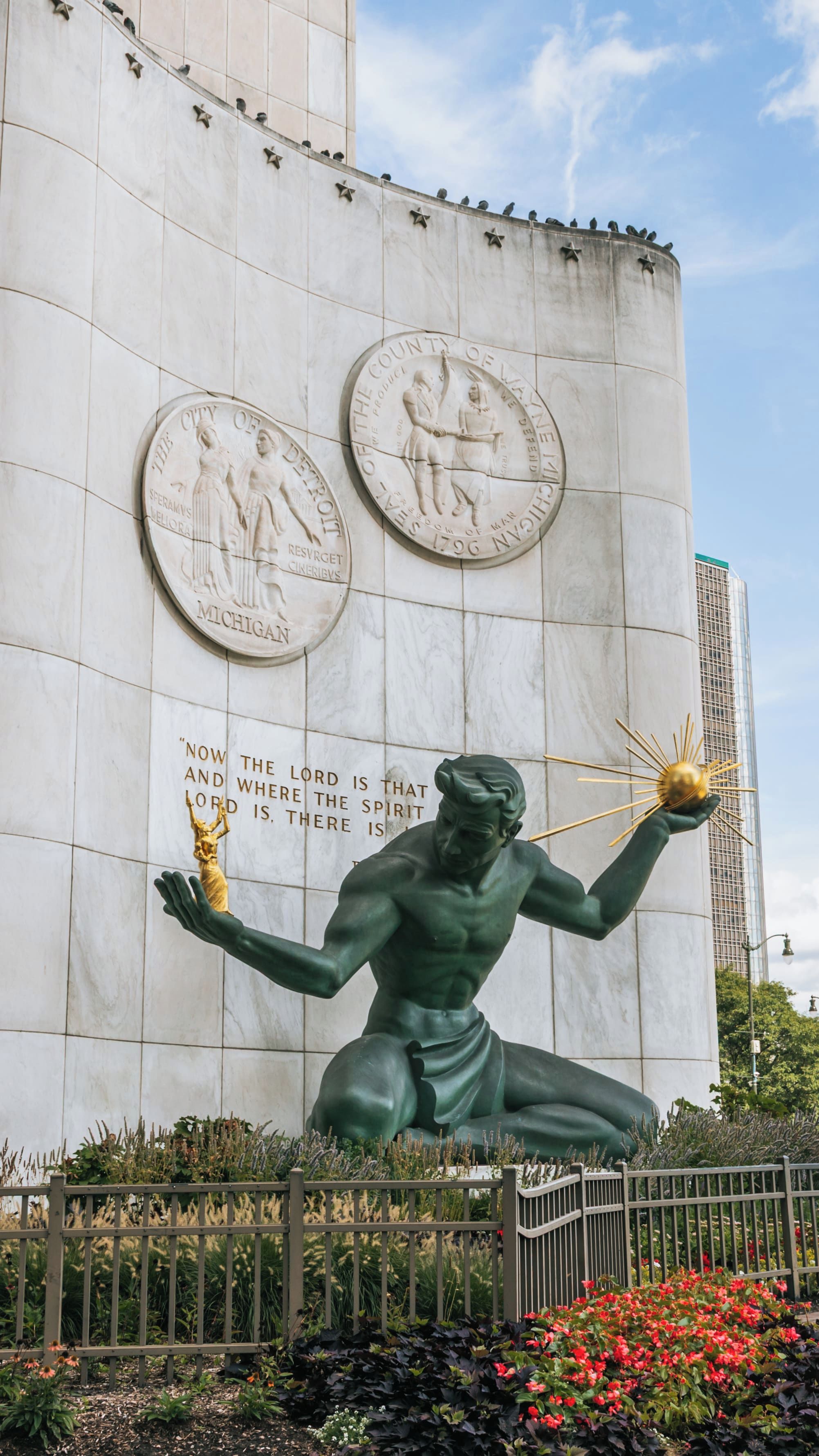 A statue of a man holding a torch with inscriptions on a building wall.