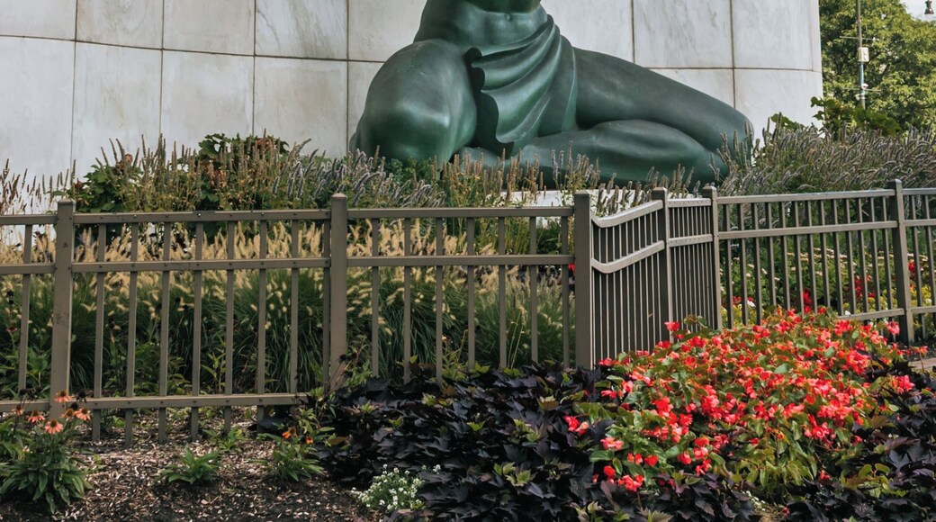 A statue of a man holding a torch with inscriptions on a building wall.
