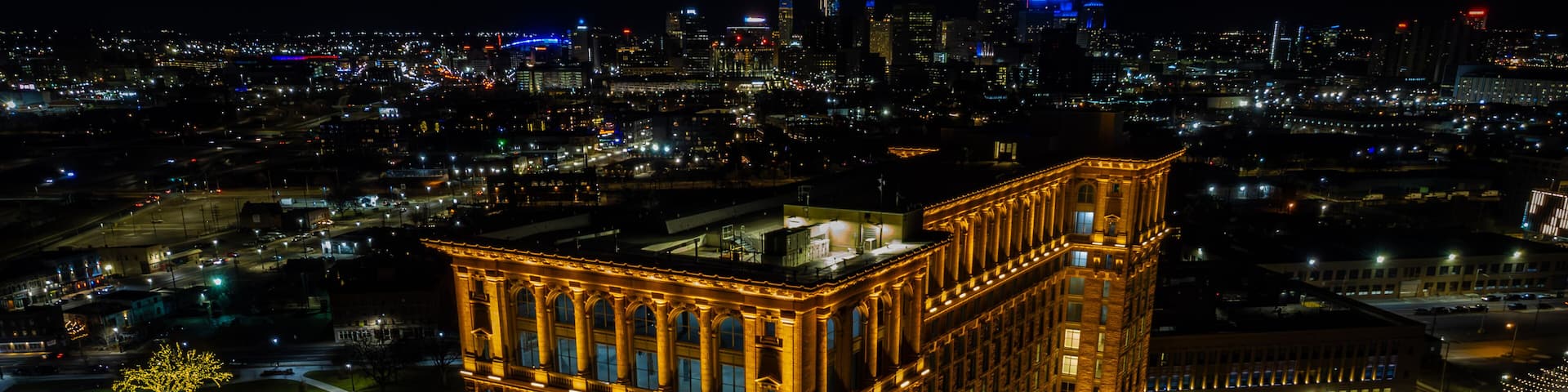 A brightly lit historic building with ornate architecture, surrounded by a cityscape at night.