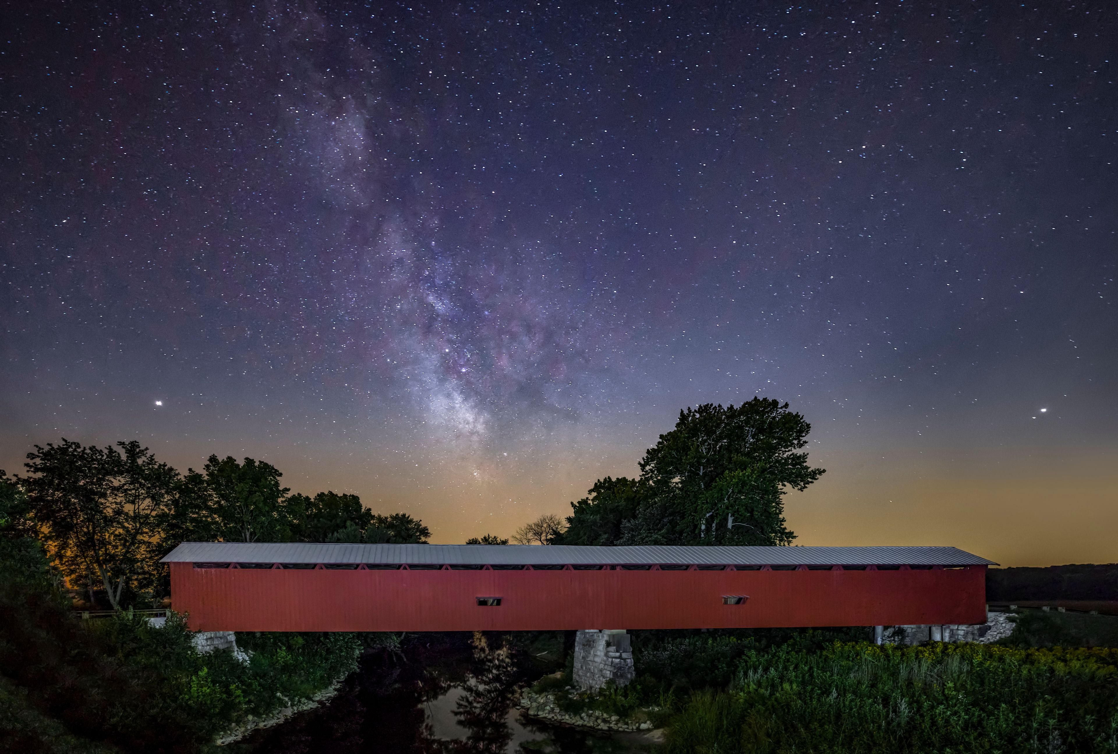 A red barn under a starry night sky with the Milky Way visible.
