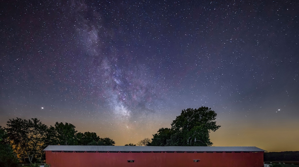 A red barn under a starry night sky with the Milky Way visible.