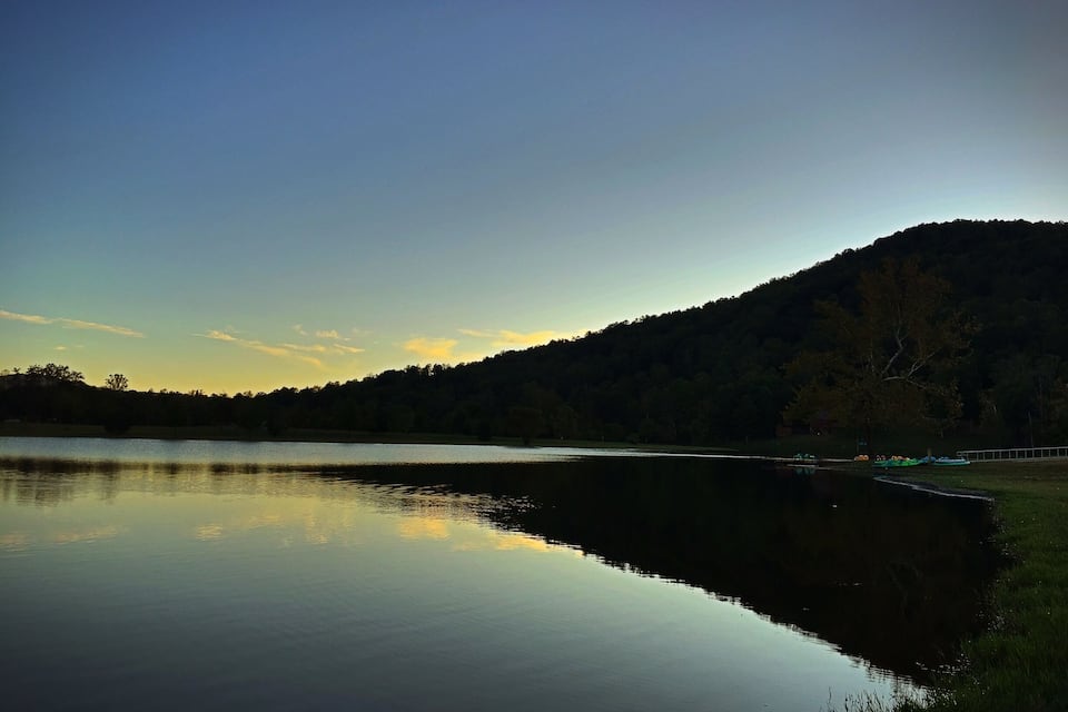 A calm lake with a forested hill in the background.