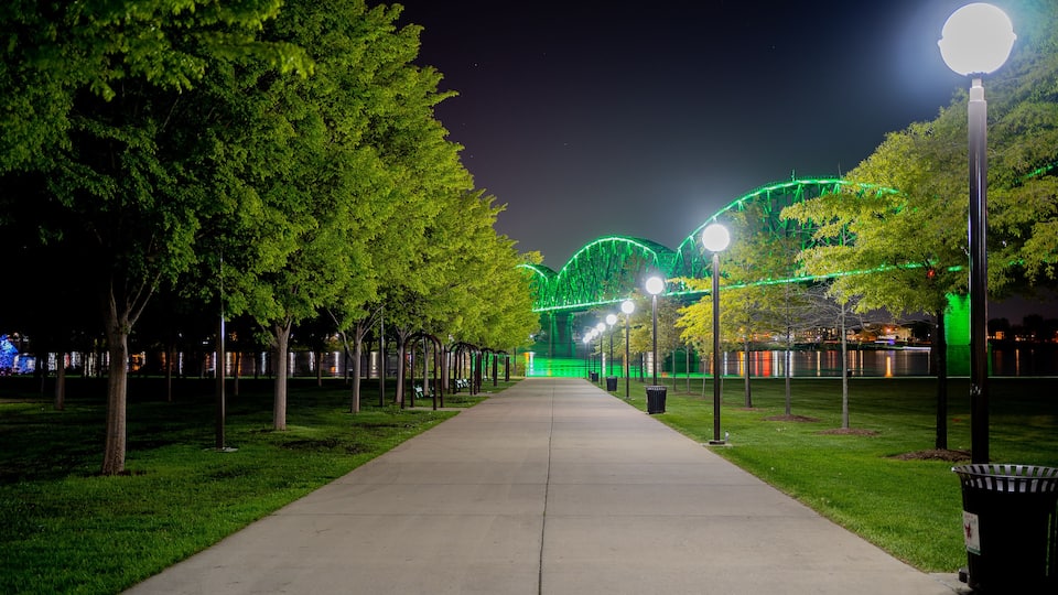 Walkway at Waterfront Park in Louisville, KY with the Big Four bridge in background lit green to mark those who have lost their lives to COVID-19.
