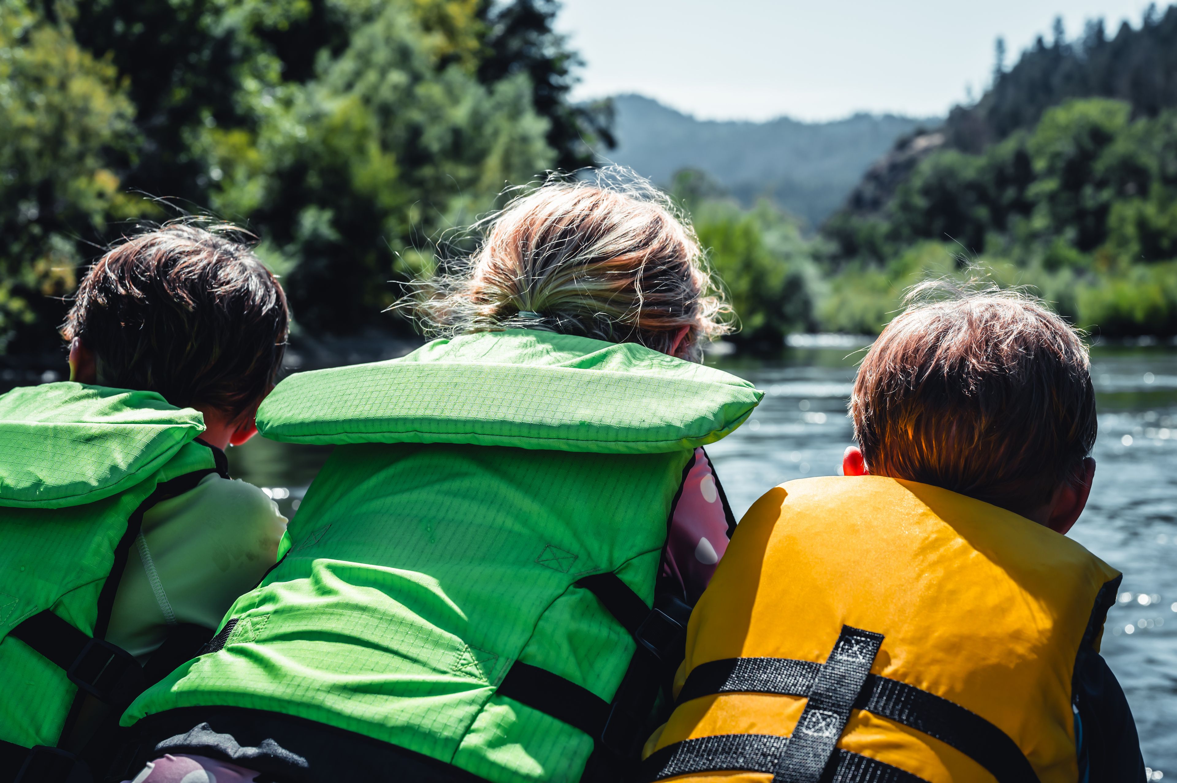 Three people wearing life jackets on a boat.