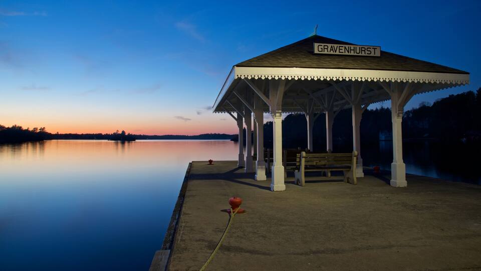 A gazebo named Gravenhurst by a calm lake at dusk.