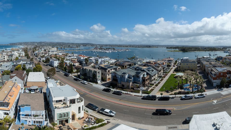 A coastal cityscape with a marina, residential buildings, and a clear blue sky.