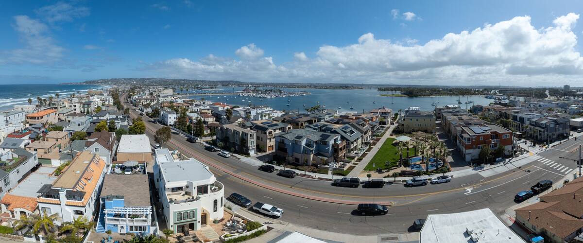 A coastal cityscape with a marina, residential buildings, and a clear blue sky.