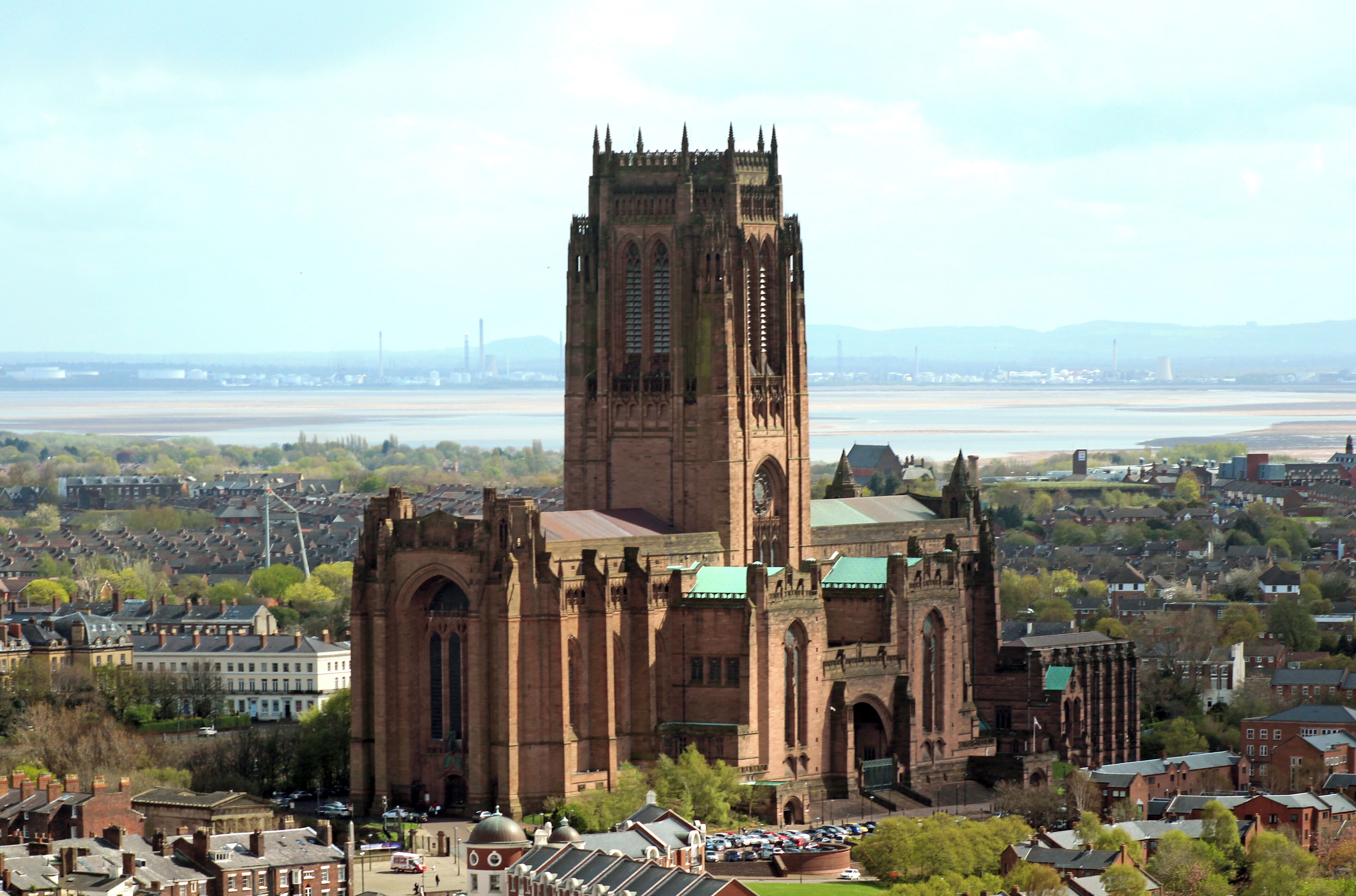 Una iglesia histórica con una alta torre y ventanas de arco, rodeada por un paisaje urbano y un río.